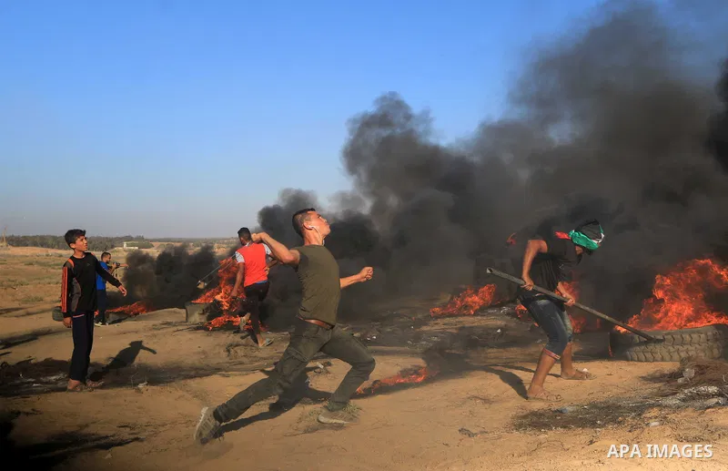 Palestinian protesters gather during clashes with Israeli troops in tents protest where Palestinians demand the right to return to their homeland at the Israel-Gaza border, in al-Bureij in the center of Gaza Strip on Sep...