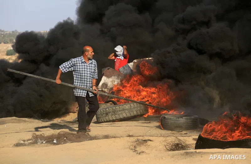 Palestinian protesters gather during clashes with Israeli troops in tents protest where Palestinians demand the right to return to their homeland at the Israel-Gaza border, in al-Bureij in the center of Gaza Strip on Sep...