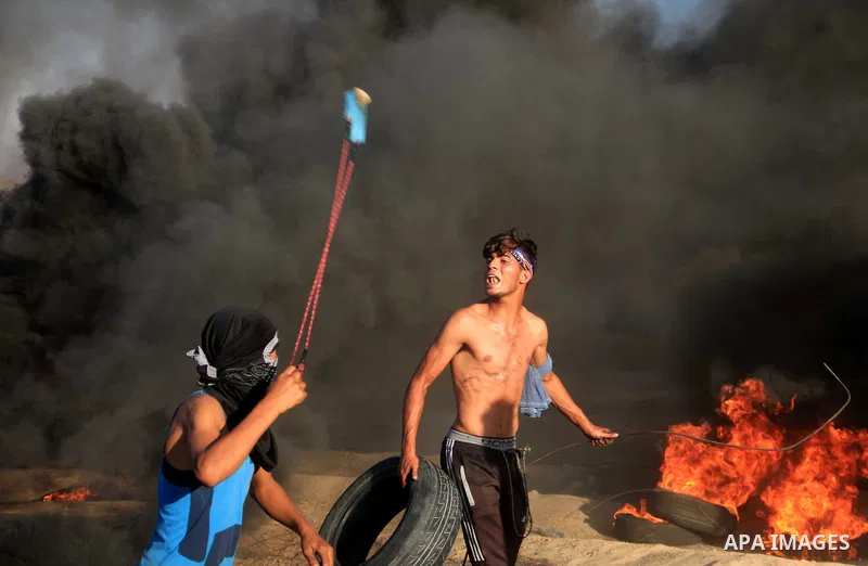 Palestinian protesters gather during clashes with Israeli troops in tents protest where Palestinians demand the right to return to their homeland at the Israel-Gaza border, in al-Bureij in the center of Gaza Strip on Sep...