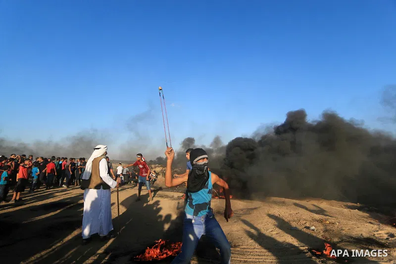 Palestinian protesters gather during clashes with Israeli troops in tents protest where Palestinians demand the right to return to their homeland at the Israel-Gaza border, in al-Bureij in the center of Gaza Strip on Sep...