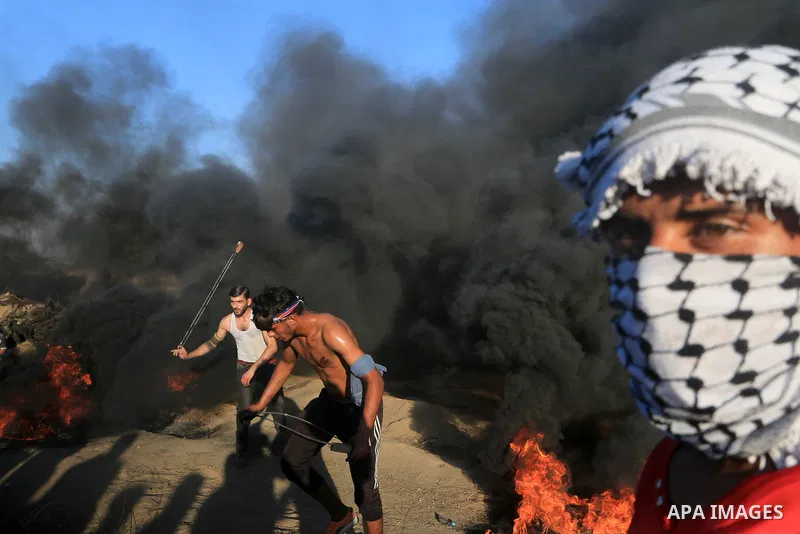 Palestinian protesters gather during clashes with Israeli troops in tents protest where Palestinians demand the right to return to their homeland at the Israel-Gaza border, in al-Bureij in the center of Gaza Strip on Sep...