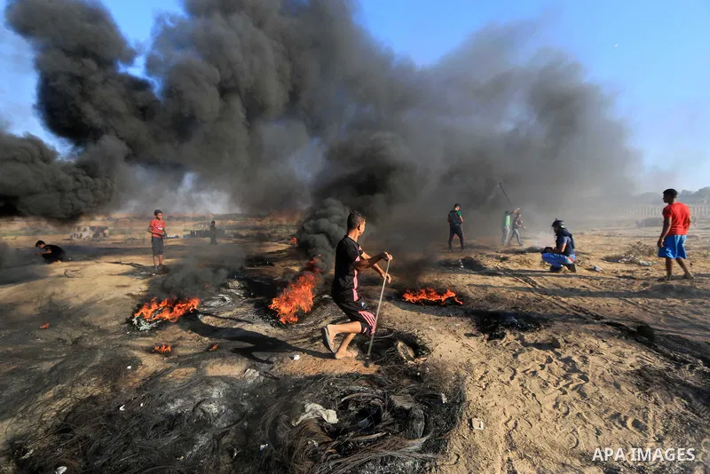 Palestinian protesters gather during clashes with Israeli troops in tents protest where Palestinians demand the right to return to their homeland at the Israel-Gaza border, in al-Bureij in the center of Gaza Strip on Sep...