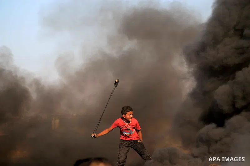 Palestinian protesters gather during clashes with Israeli troops in tents protest where Palestinians demand the right to return to their homeland at the Israel-Gaza border, in al-Bureij in the center of Gaza Strip on Sep...