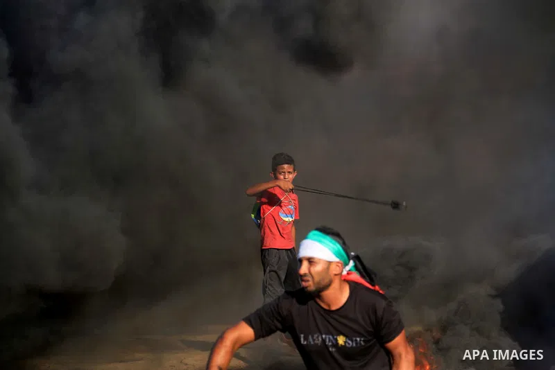 Palestinian protesters gather during clashes with Israeli troops in tents protest where Palestinians demand the right to return to their homeland at the Israel-Gaza border, in al-Bureij in the center of Gaza Strip on Sep...