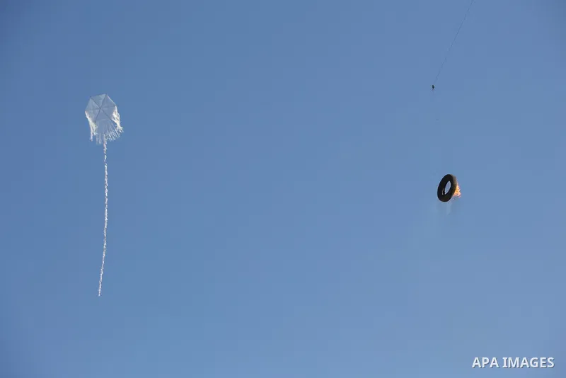 A kite laden with a burning tire is seen flew over the border before cutting the string leaving the burning material to fall in Israeli territory during clashes between Palestinian protesters and Israeli troops in tents...