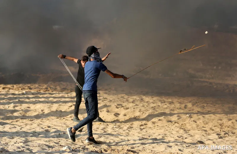 A Palestinian protester uses a slingshot to hurl stones towards Israeli forces during clashes in a demonstration against the Israeli blockade on Gaza Strip, along the Gaza sea barrier on the maritime border with Israel n...