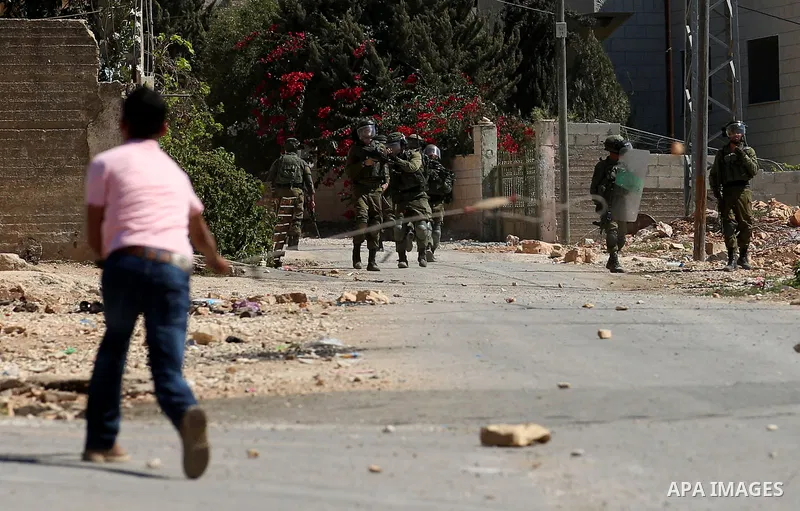 A Palestinian protester uses a slingshot to hurl stones towards Israeli forces during clashes following a weekly demonstration against the expropriation of Palestinian land by Israel in the village of Kfar Qaddum, near t...