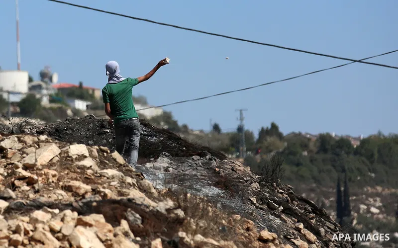 A Palestinian protester hurls stones towards Israeli forces during clashes following a weekly demonstration against the expropriation of Palestinian land by Israel in the village of Kfar Qaddum, near the West Bank city o...