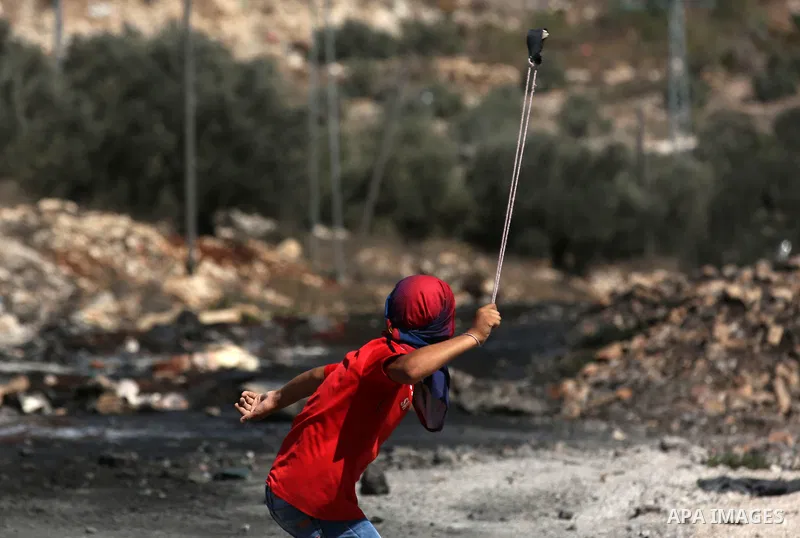 A Palestinian protester uses a slingshot to hurl stones towards Israeli forces during clashes following a weekly demonstration against the expropriation of Palestinian land by Israel in the village of Kfar Qaddum, near t...