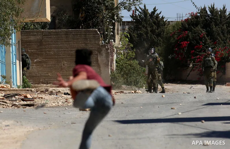 A Palestinian protester uses a slingshot to hurl stones towards Israeli forces during clashes following a weekly demonstration against the expropriation of Palestinian land by Israel in the village of Kfar Qaddum, near t...