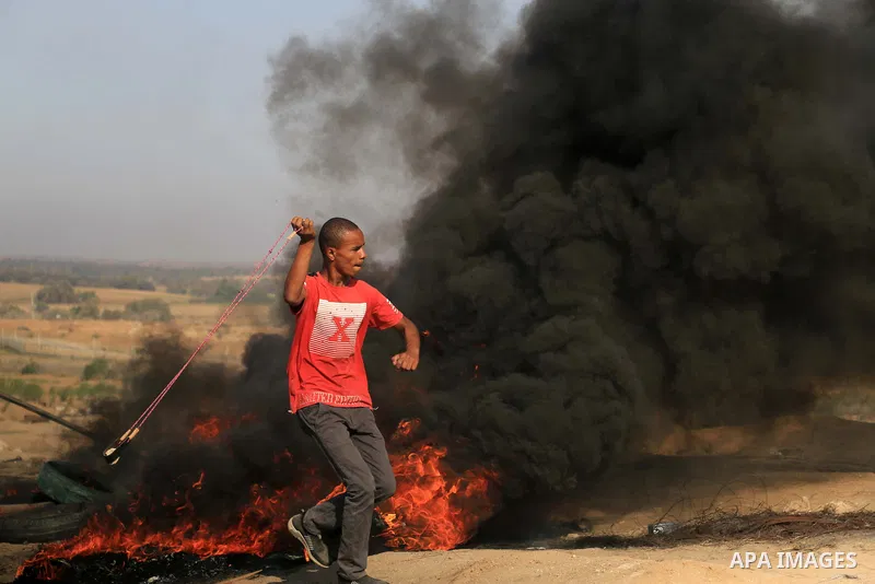 Palestinian protesters gather during clashes with Israeli troops in tents protest where Palestinians demand the right to return to their homeland at the Israel-Gaza border, in al-Bureij in the center of Gaza Strip on Sep...