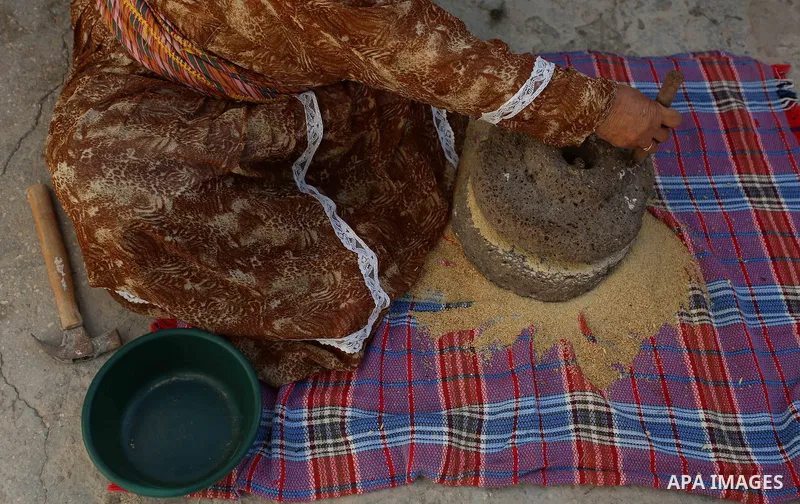 A picture taken on September 22, 2018 shows a Palestinian woman grinds wheat by a stone mill, inside her house, in the village of Jalbun near the West Bank City of Jenin. Photo by Shadi Jarar'ah
