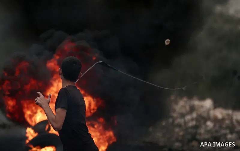 A Palestinian protester uses a slingshot to hurl stones towards Israeli troops during clashes against Israel's Nation State Law, and Israel's plan to demolish the Khan al-Ahmar village, in the village of Kfar Qaddum, nea...