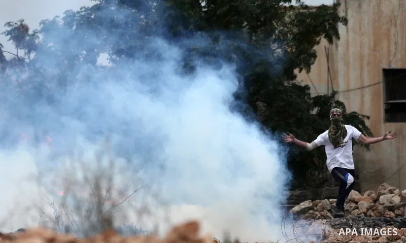 A Palestinian protester reacts to tear gas fired by Israeli troops during clashes against Israel's Nation State Law, and Israel's plan to demolish the Khan al-Ahmar village in the village of Kfar Qaddum, near the West Ba...