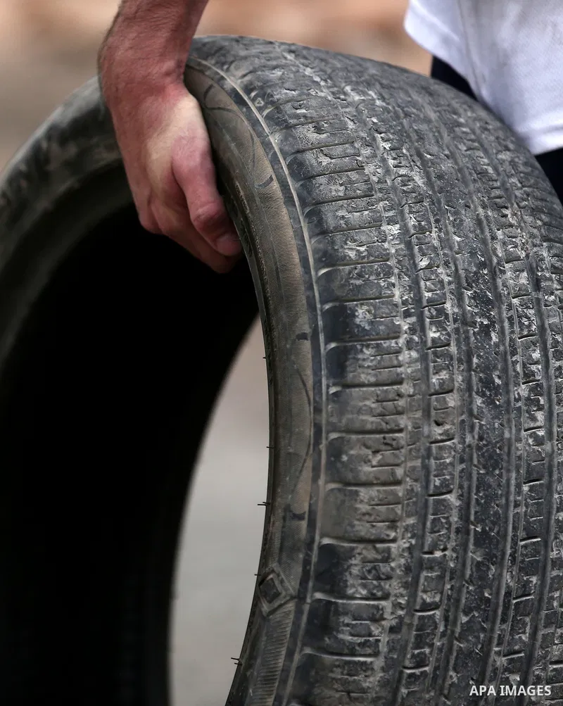 A Palestinian protester carries a tire during clashes with Israeli troops against Israel's Nation State Law, and Israel's plan to demolish the Khan al-Ahmar village in the village of Kfar Qaddum, near the West Bank city...
