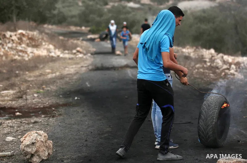 Palestinian protesters burn tires during clashes with Israeli troops against Israel's Nation State Law, and Israel's plan to demolish the Khan al-Ahmar village in the village of Kfar Qaddum, near the West Bank city of Na...