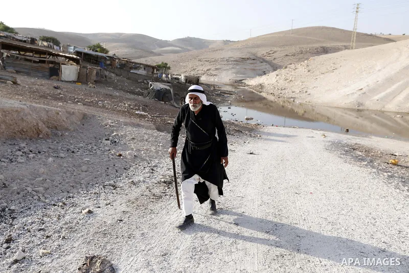 Palestinians walk near a wastewater pond, at the Palestinian Bedouin village of Khan al-Ahmar which Israel plan to demolish, in the occupied West Bank, on October 2, 2018. Photo by Wisam Hashlamoun
