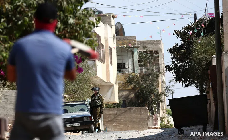 A Palestinian protester hurls stones towards Israeli forces during clashes following a weekly demonstration against the expropriation of Palestinian land by Israel in the village of Kfar Qaddum, near the West Bank city o...