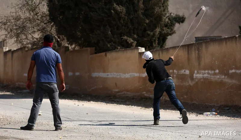 A Palestinian protester uses a slingshot to hurl stones towards Israeli forces during clashes following a weekly demonstration against the expropriation of Palestinian land by Israel in the village of Kfar Qaddum, near t...