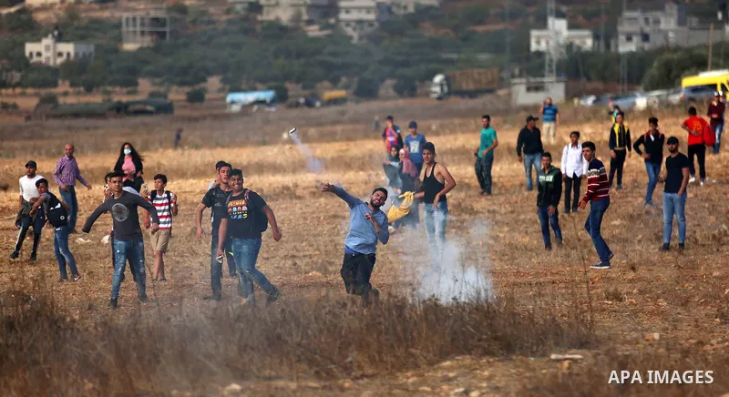 Palestinians throw back a tear gas canister fired by Israeli soldiers during clashes over an Israeli order to shut down a Palestinian school in the West Bank city of Nablus, on October 15, 2018. Photo by Shadi Jarar'ah