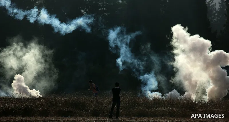 Palestinians throw back a tear gas canister fired by Israeli soldiers during clashes over an Israeli order to shut down a Palestinian school in the West Bank city of Nablus, on October 15, 2018. Photo by Shadi Jarar'ah