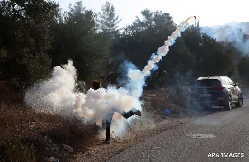 Palestinians throw back a tear gas canister fired by Israeli soldiers during clashes over an Israeli order to shut down a Palestinian school in the West Bank city of Nablus, on October 15, 2018. Photo by Shadi Hatem