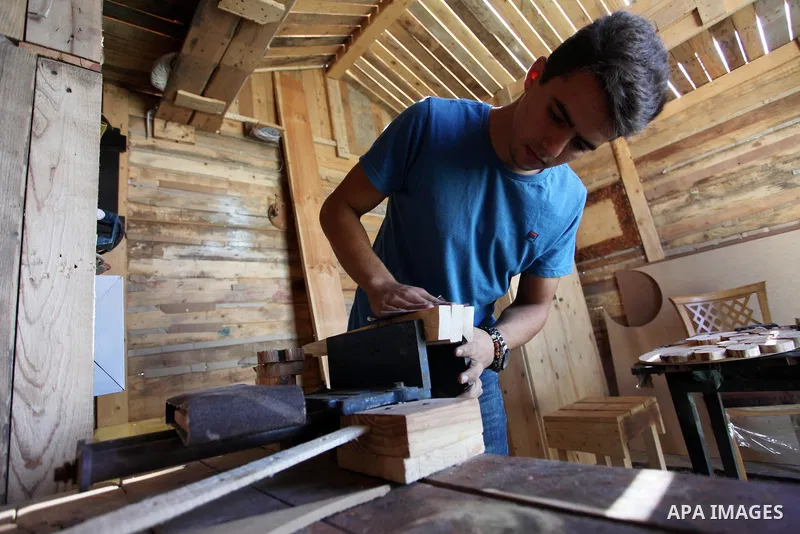 A Palestinian Nedal al-Nakhala, 20, works at a workshop "Antica Home", where he manufactures wooden products to sell it for customers, in Gaza City on October 16, 2018. Photo by Mahmoud Ajjour
