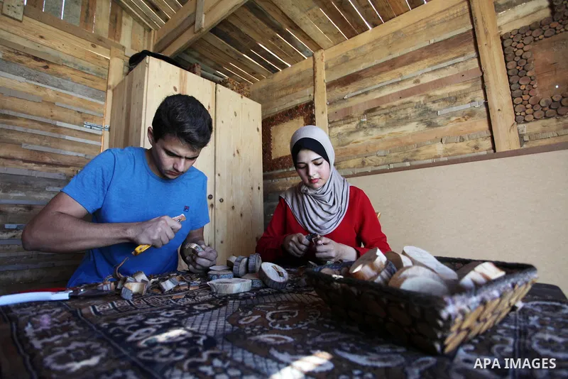 A Palestinian Nedal al-Nakhala, 20, and his sister Heba, 22, work at their workshop "Antica Home", where they manufacture wooden products to sell it for customers, in Gaza City on October 16, 2018. Photo by Mahmoud Ajjou...