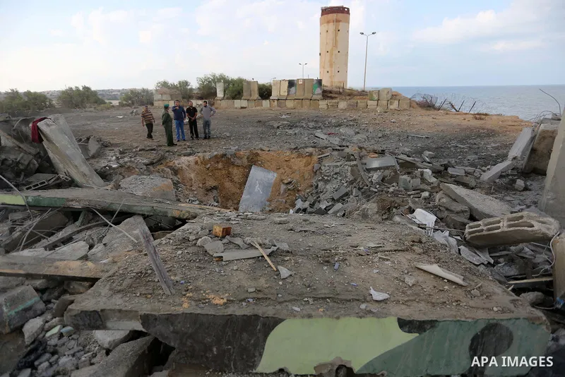 Palestinian men inspect the site targeted by an Israeli air strike, in Rafah in the southern Gaza strip on October 17, 2018. Photo by Ashraf Amra