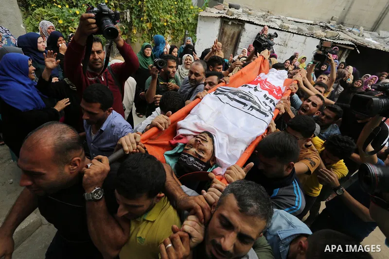 Mourners carry the body of Palestinian Naji Al-Zaanin, 25, who was killed in an Israeli airstrike during his funeral in Beit Hanoun in the northern Gaza Strip on October 17, 2018. Photo by Ashraf Amra