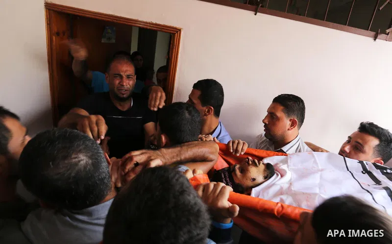 Mourners carry the body of Palestinian Naji Al-Zaanin, 25, who was killed in an Israeli airstrike during his funeral in Beit Hanoun in the northern Gaza Strip on October 17, 2018. Photo by Ashraf Amra