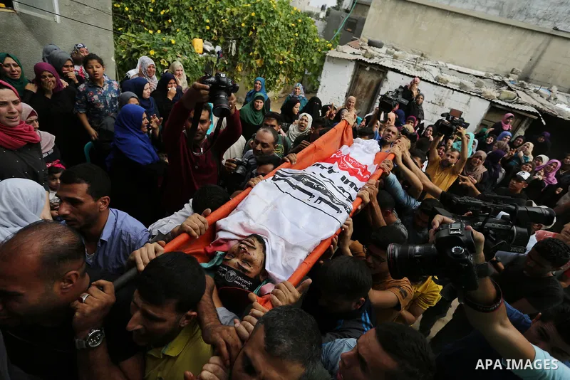 Mourners carry the body of Palestinian Naji Al-Zaanin, 25, who was killed in an Israeli airstrike during his funeral in Beit Hanoun in the northern Gaza Strip on October 17, 2018. Photo by Ashraf Amra