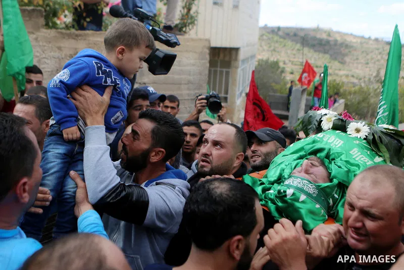 Mourners carry the body of Palestinian Othman Ladadwah, who was shot dead by Israeli forces during clashes the day before, during his funeral in the village of Al-Mazraa Al-Gharbeya, in the West Bank city of Ramallah on...