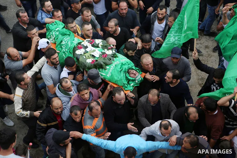 Mourners carry the body of Palestinian Othman Ladadwah, who was shot dead by Israeli forces during clashes the day before, during his funeral in the village of Al-Mazraa Al-Gharbeya, in the West Bank city of Ramallah on...