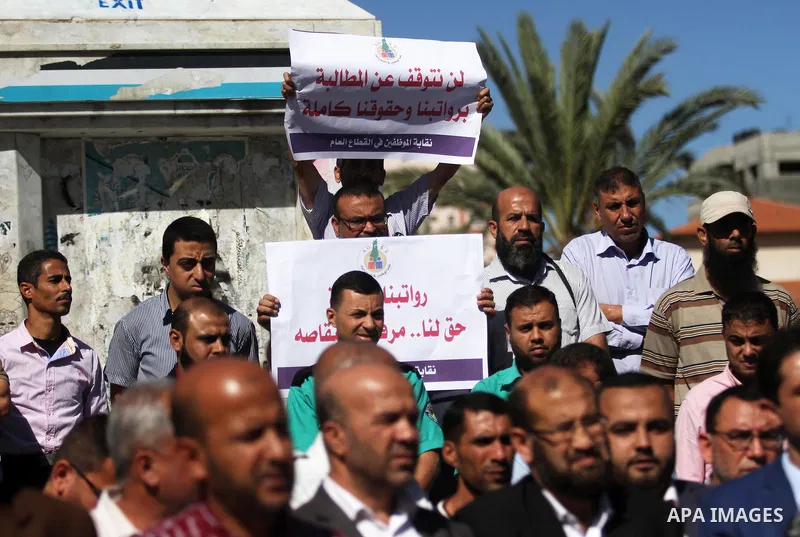 Palestinian employees of Gaza strip hold banners during a protest demanding their salaries, in Gaza city on October 28, 2018. Photo by Mahmoud Ajjour