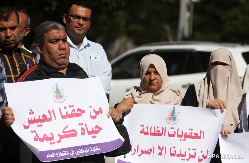 Palestinian employees of Gaza strip hold banners during a protest demanding their salaries, in Gaza city on October 28, 2018. Photo by Mahmoud Ajjour