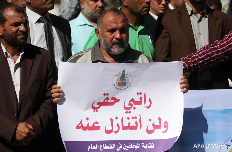Palestinian employees of Gaza strip hold banners during a protest demanding their salaries, in Gaza city on October 28, 2018. Photo by Mahmoud Ajjour