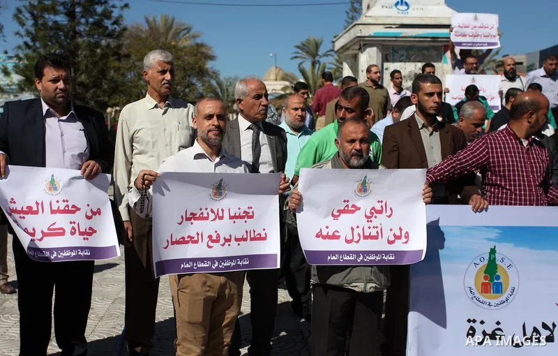 Palestinian employees of Gaza strip hold banners during a protest demanding their salaries, in Gaza city on October 28, 2018. Photo by Mahmoud Ajjour