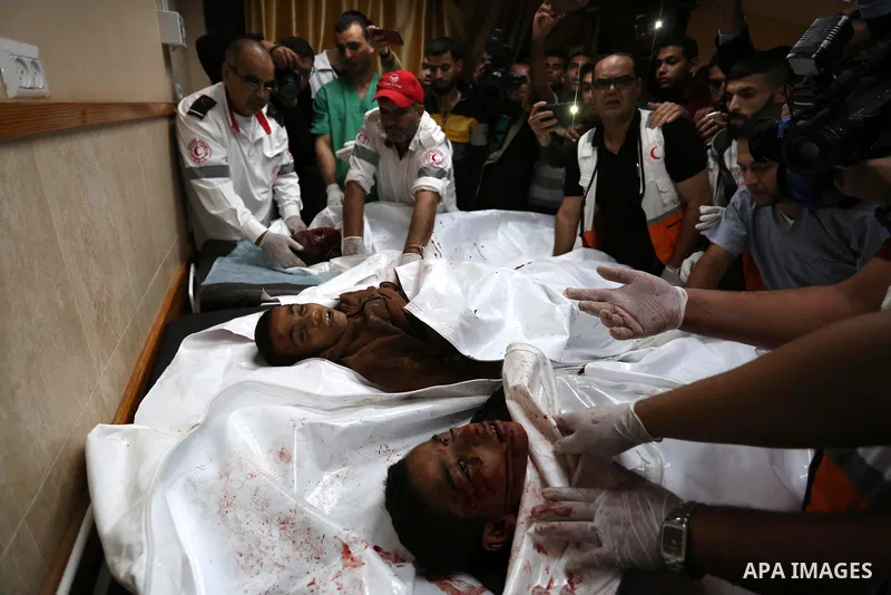 Palestinians look at the bodies of three Palestinians killed in an Israeli air strike on the Gaza Strip, at the morgue of Al-Aqsa Hospital in Deir al-Balah in the central Gaza Strip on October 28, 2018. Photo by Ashraf A...
