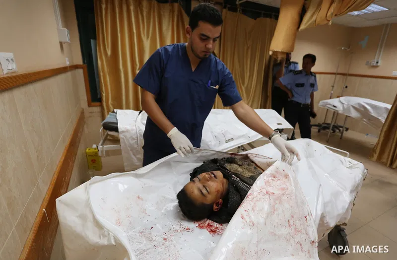 Palestinians look at the bodies of three Palestinians killed in an Israeli air strike on the Gaza Strip, at the morgue of Al-Aqsa Hospital in Deir al-Balah in the central Gaza Strip on October 28, 2018. Photo by Ashraf A...