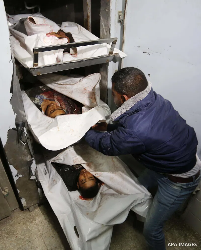 Palestinians look at the bodies of three Palestinians killed in an Israeli air strike on the Gaza Strip, at the morgue of Al-Aqsa Hospital in Deir al-Balah in the central Gaza Strip on October 28, 2018. Photo by Ashraf A...