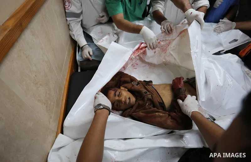 Palestinians look at the bodies of three Palestinians killed in an Israeli air strike on the Gaza Strip, at the morgue of Al-Aqsa Hospital in Deir al-Balah in the central Gaza Strip on October 28, 2018. Photo by Ashraf A...