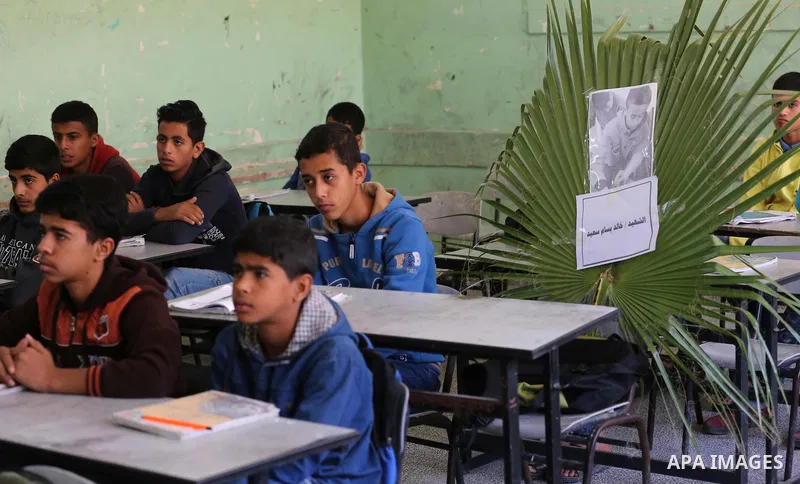 A picture of Palestinian boy Khaled Saed,14, who was killed in an Israeli air strike on the Gaza Strip, is seen on his study seat next to his classmates at a school, in Deir al-Balah in the central Gaza Strip, on October...
