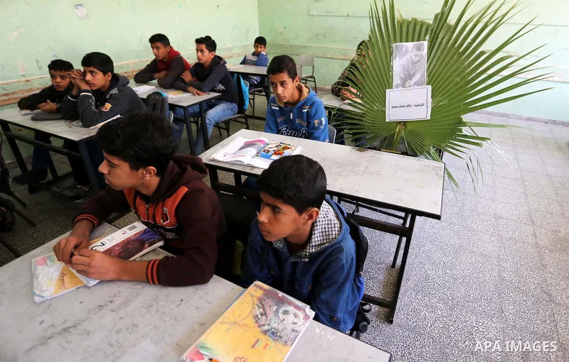 A picture of Palestinian boy Khaled Saed,14, who was killed in an Israeli air strike on the Gaza Strip, is seen on his study seat next to his classmates at a school, in Deir al-Balah in the central Gaza Strip, on October...