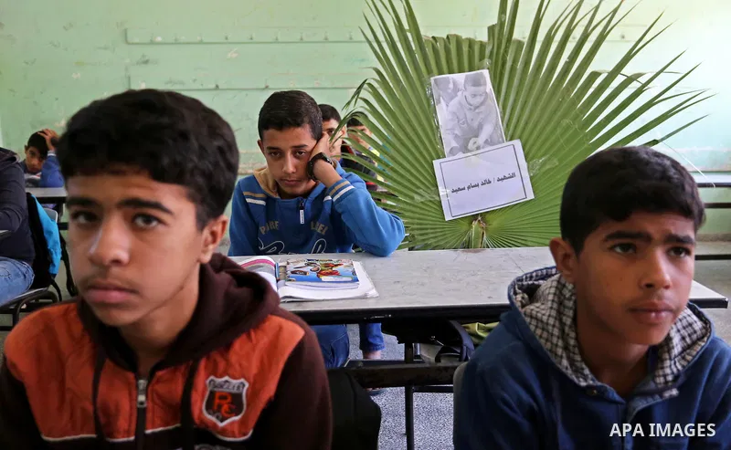 A picture of Palestinian boy Khaled Saed,14, who was killed in an Israeli air strike on the Gaza Strip, is seen on his study seat next to his classmates at a school, in Deir al-Balah in the central Gaza Strip, on October...