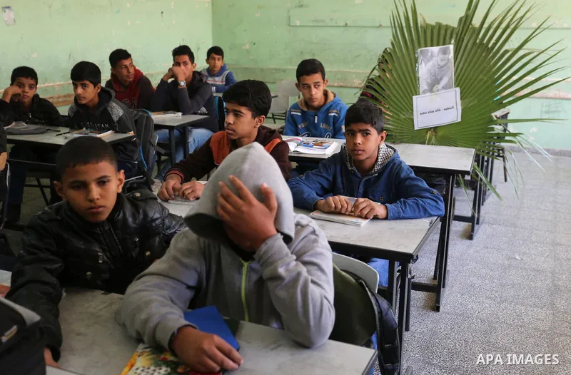 A picture of Palestinian boy Khaled Saed,14, who was killed in an Israeli air strike on the Gaza Strip, is seen on his study seat next to his classmates at a school, in Deir al-Balah in the central Gaza Strip, on October...