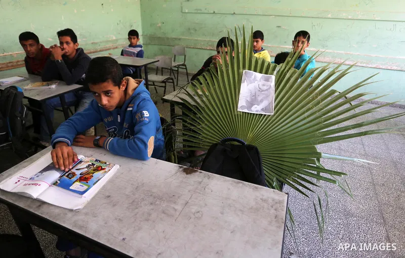 A picture of Palestinian boy Khaled Saed,14, who was killed in an Israeli air strike on the Gaza Strip, is seen on his study seat next to his classmates at a school, in Deir al-Balah in the central Gaza Strip, on October...