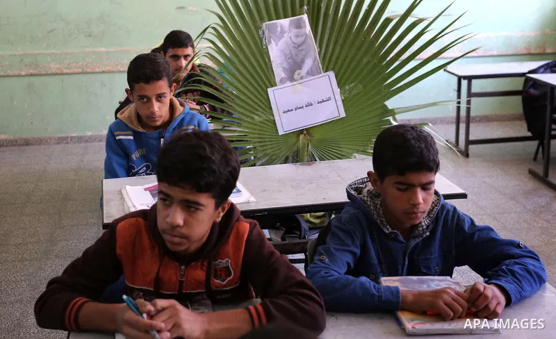 A picture of Palestinian boy Khaled Saed,14, who was killed in an Israeli air strike on the Gaza Strip, is seen on his study seat next to his classmates at a school, in Deir al-Balah in the central Gaza Strip, on October...