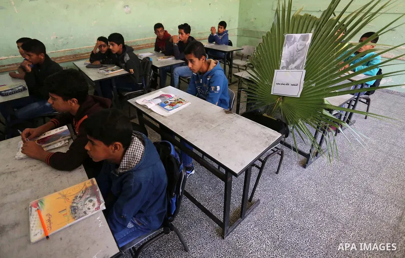 A picture of Palestinian boy Khaled Saed,14, who was killed in an Israeli air strike on the Gaza Strip, is seen on his study seat next to his classmates at a school, in Deir al-Balah in the central Gaza Strip, on October...