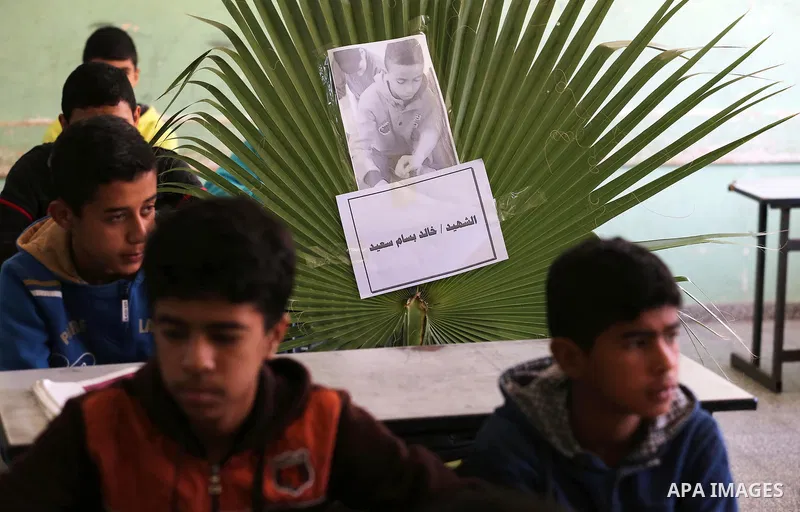 A picture of Palestinian boy Khaled Saed,14, who was killed in an Israeli air strike on the Gaza Strip, is seen on his study seat next to his classmates at a school, in Deir al-Balah in the central Gaza Strip, on October...